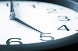 Close up on clock with hour hand pointing at 5