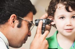 A doctor looking into a young boy's ear to check his hearing