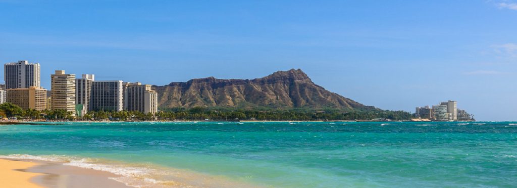 Photo of a Waikiki Beach with buildings and mountain in the background