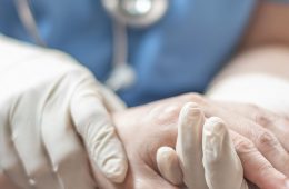 Close up on doctor with gloves holds patient's hand