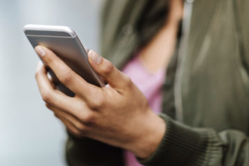 Close up photo of a young woman holding her phone