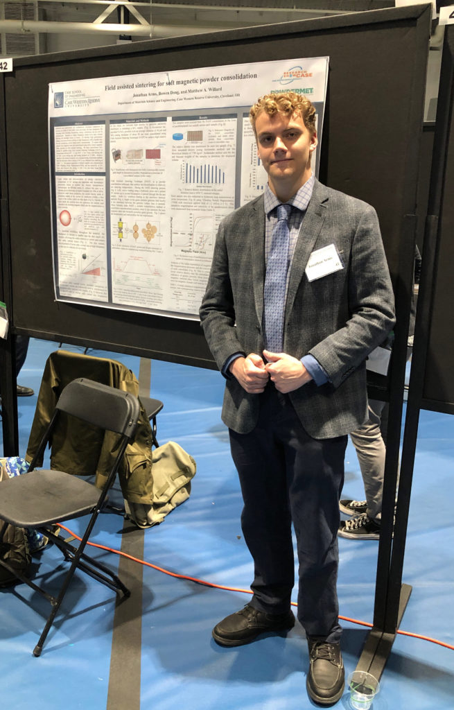 Photo of Jonathan Arms standing next to a poster presentation