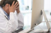 physician exhausted in front of a computer
