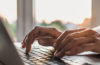 hands typing on a laptop keyboard