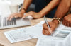 Photo showing hands pointing to financial documents on a table