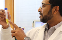 Photograph of researcher Anirban Sen Gupta pointing at a vial