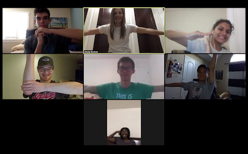 Screenshot of a Zoom meeting with seven students participating in the Human Centered Design class, forming their arms into a combined shape together